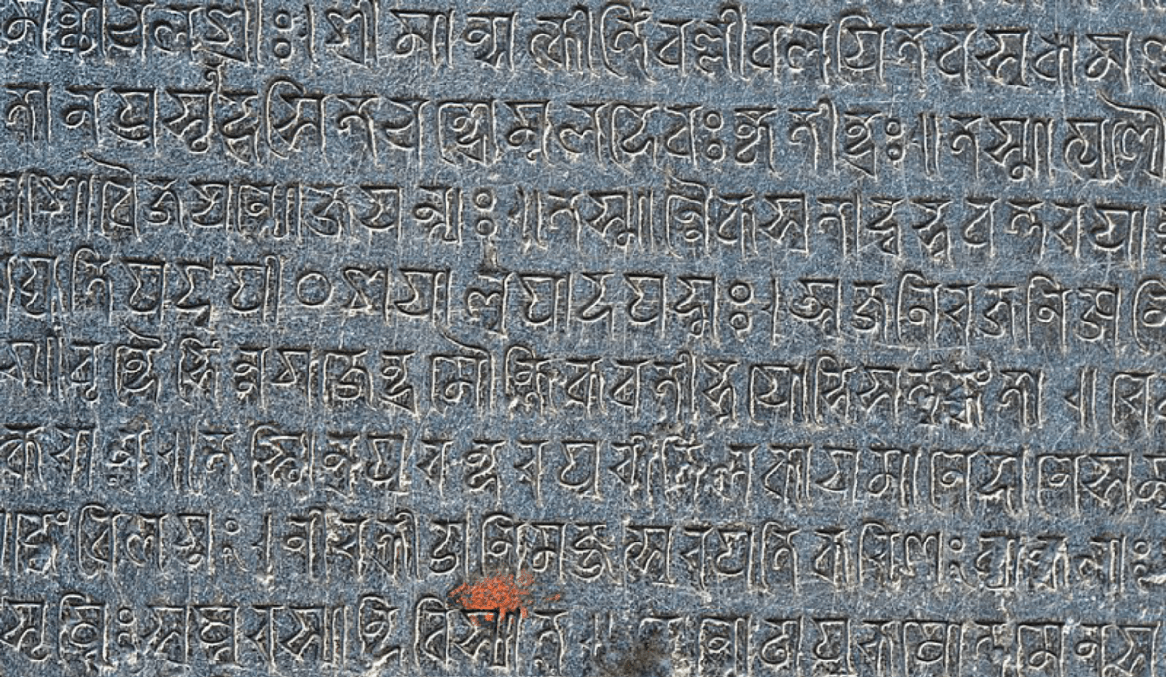 A close-up photograph of an ancient Odia stone inscription